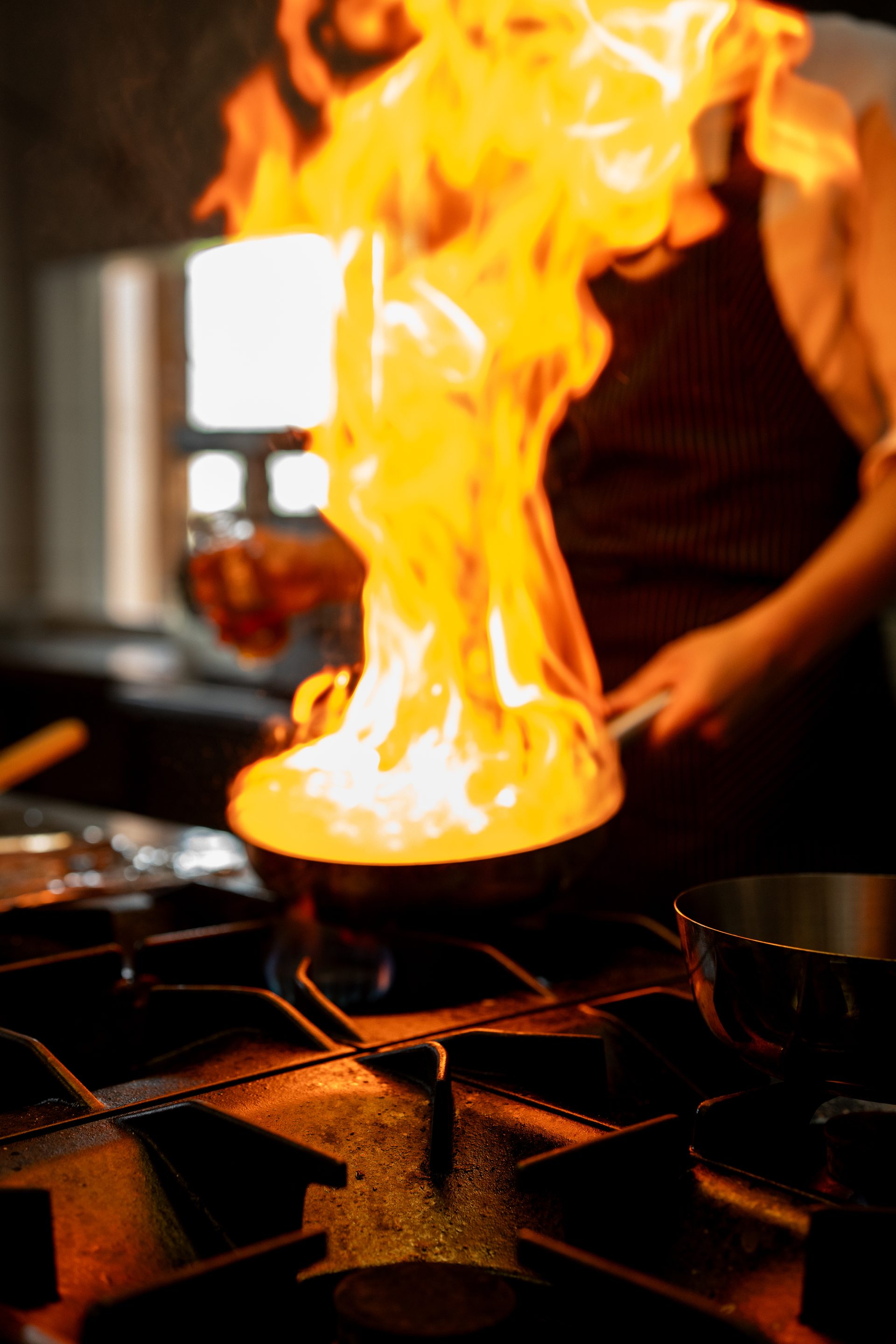 Chef flambéing in La Ursula kitchen — flames above the pan