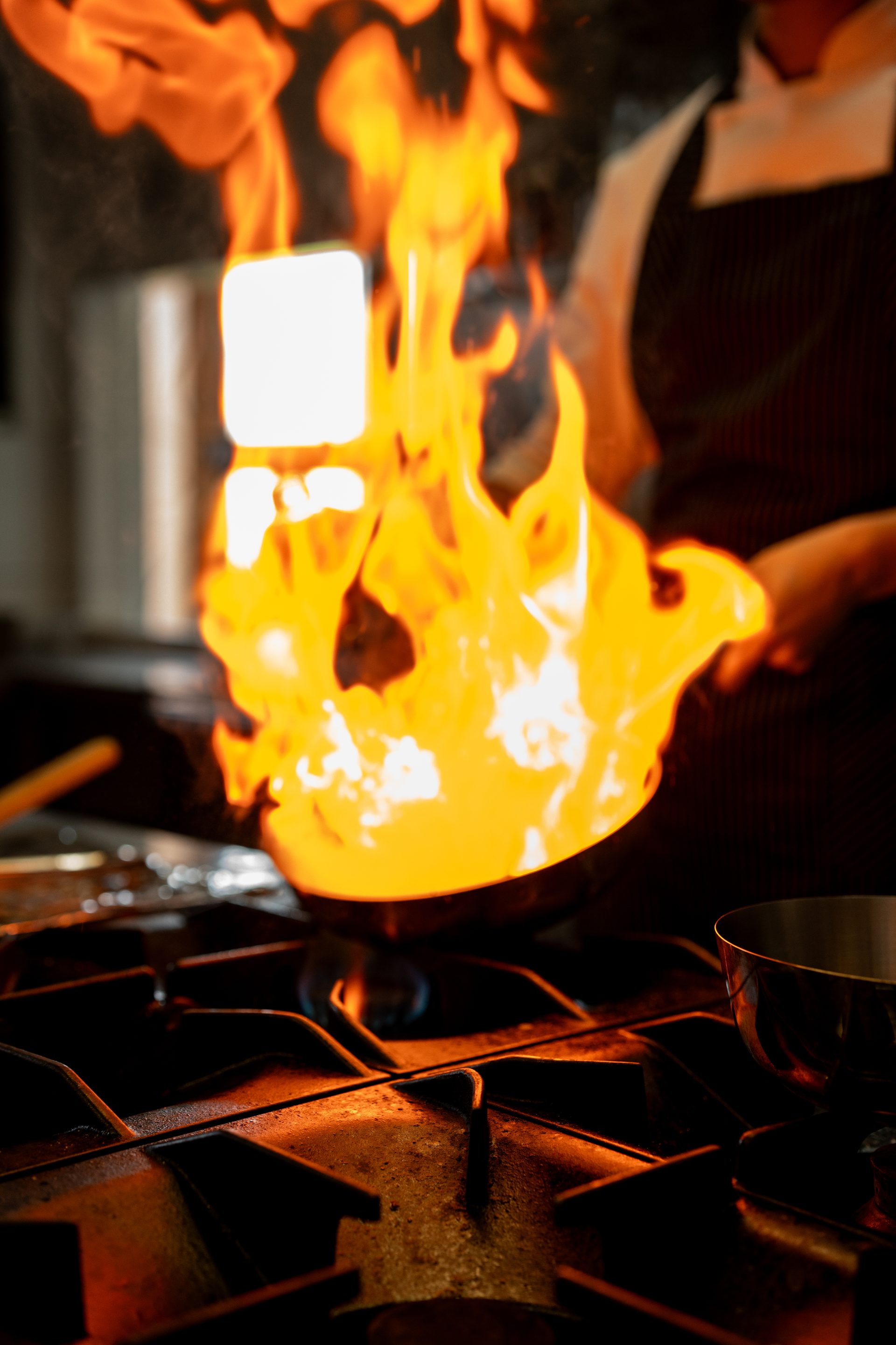 Chef flambéing over open flame at La Ursula kitchen
